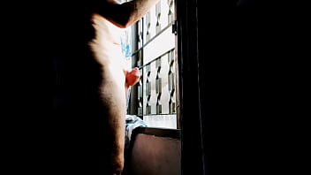 窓の前でチンポをマッサージする男性。